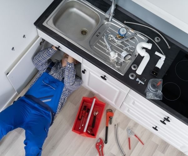 Techniker der Rohrreinigung Rudolf im Einsatz – Abfluss wird direkt unter der Spüle gereinigt